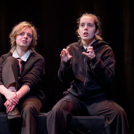 Two young performers on sat on stage talking.