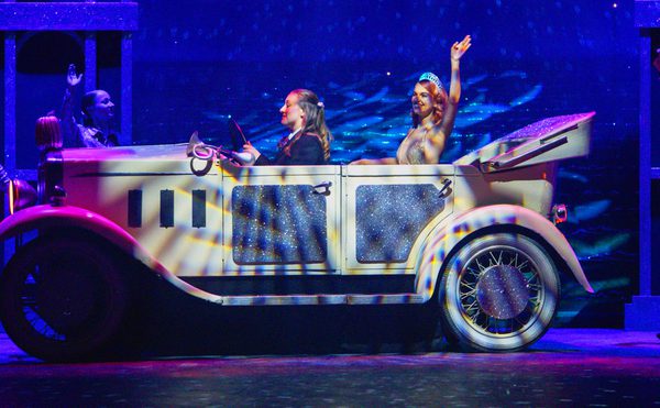 Cinderella in a car waving, on stage.
