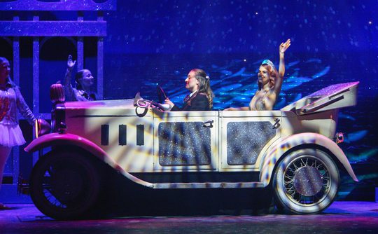 Cinderella in a car waving, on stage.