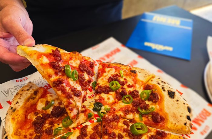 A person taking a slice of pizza.