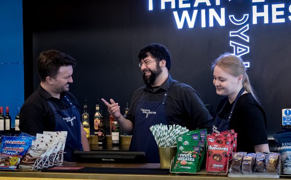 Three bar team members laughing and joking around behind the theatre bar.