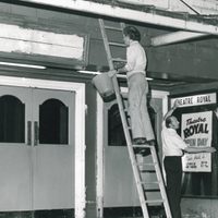 A group of people painting and decorating the front of the theatre.
