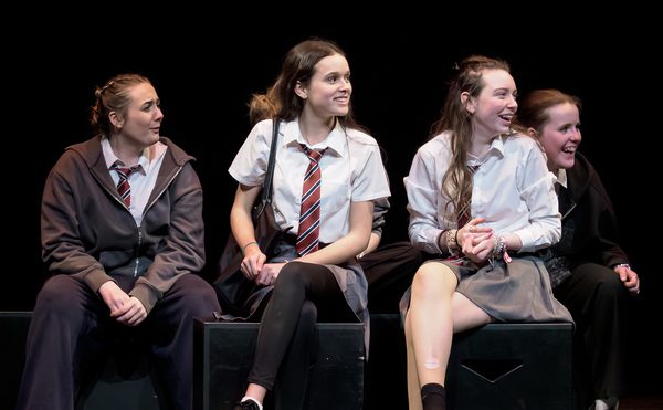 Young performers in school uniform on stage and looking happy.