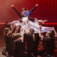 A group of young people performing on stage with fabric and masks.