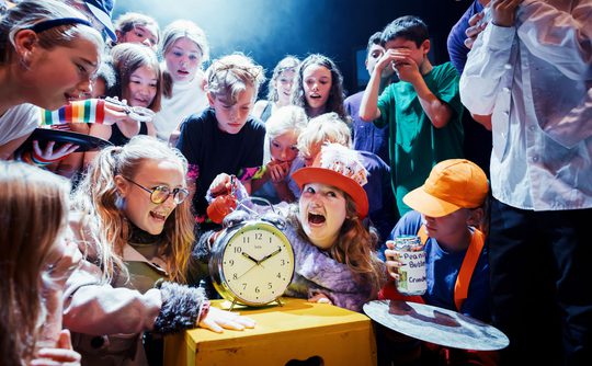 A group of young people looking at an alarm clock.