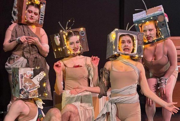 A group of young performers wearing televisions on their heads.
